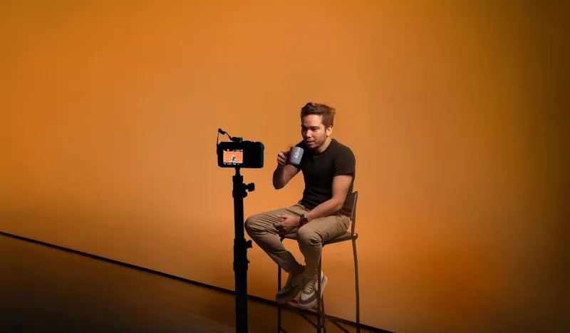 Gravação de vídeo com celular no tripé e fundo iluminado em laranja