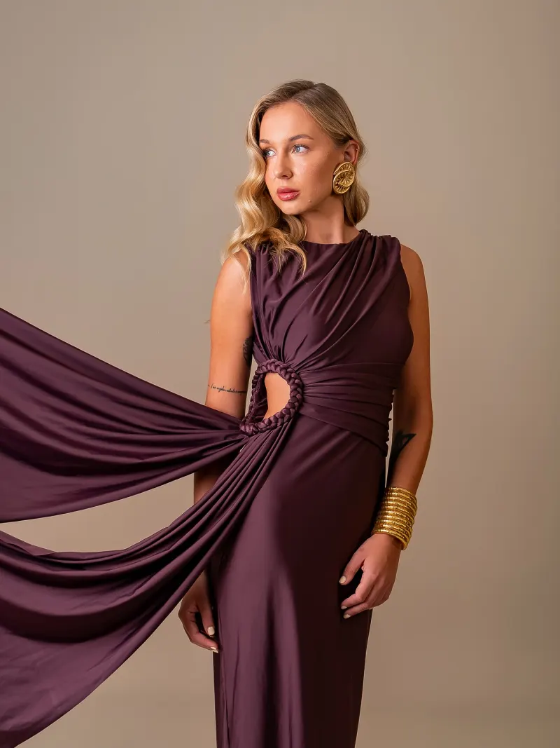Modelo com vestido vinho e tecido em movimento no fundo infinito